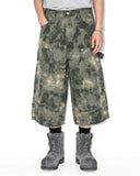 Front view of washed camo utility longline shorts with curved pocket seams and rivet details